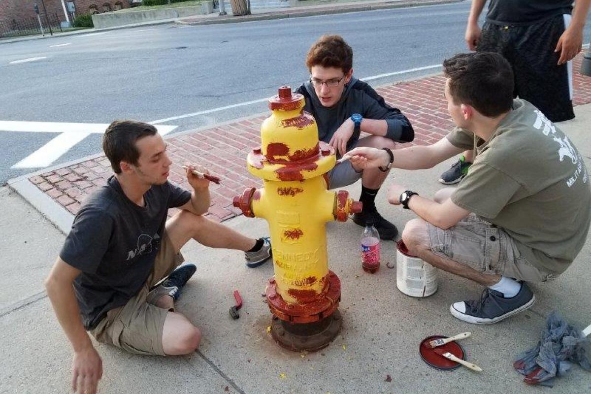 Group of 3 boys surrounding fire hydrant, painting