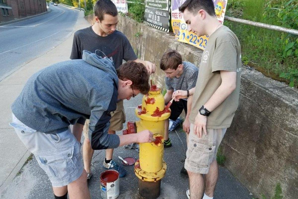 Group of 4 boys surrounding fire hydrant, painting